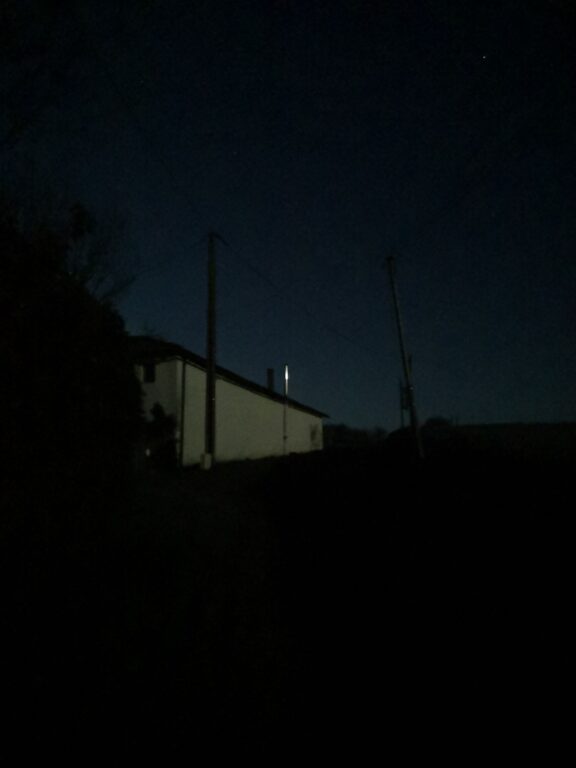 White house in the darkness surrounding it with the moonlight reflection on a metal chimney. 